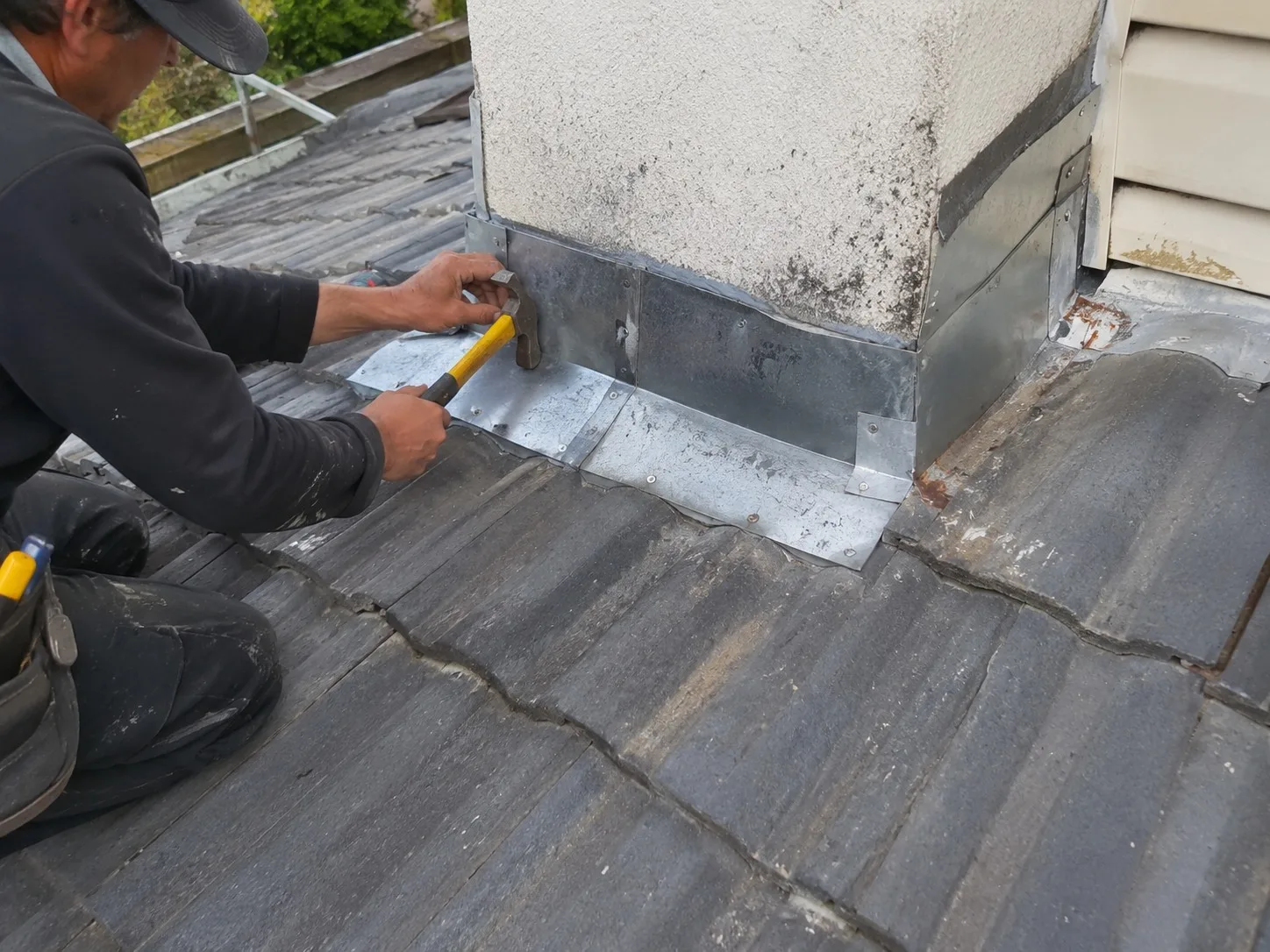 Roofer replacing a wall flashing on a West Auckland home