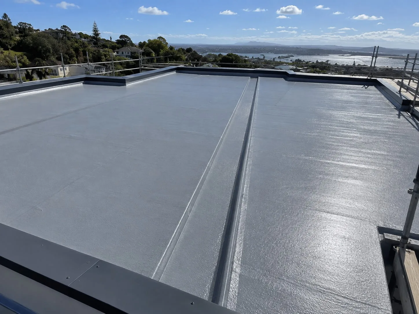 Roofer laying a membrane roof on a low-pitch West Auckland home